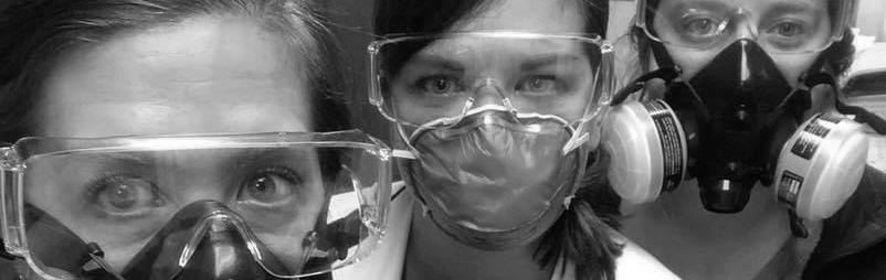 Three healthcare workers pose for a shot in their full PPE gear