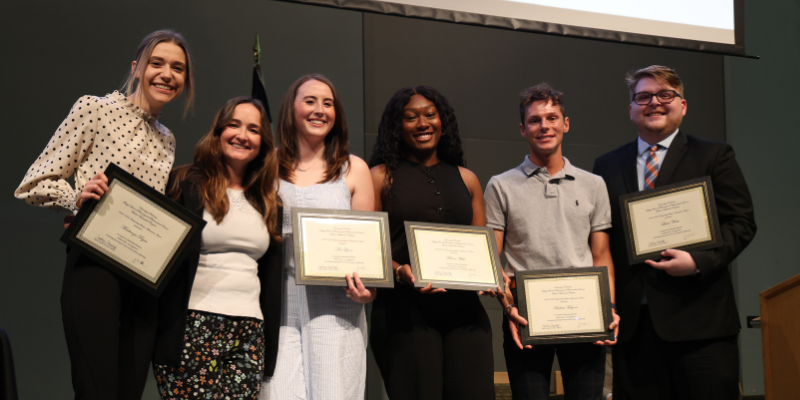 Pharmacy students display their awards on stage.
